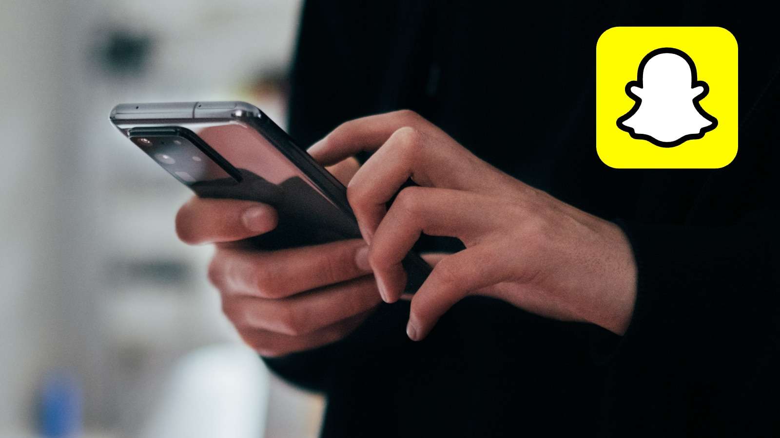 Telefon tutan ellerin yanında Snapchat logosu